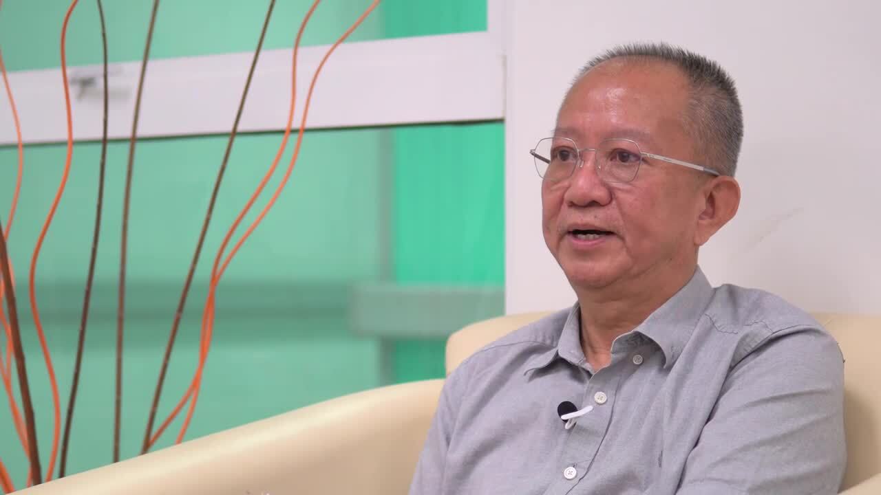 Dr Loo, a Malaysian man sitting in a chair telling his story